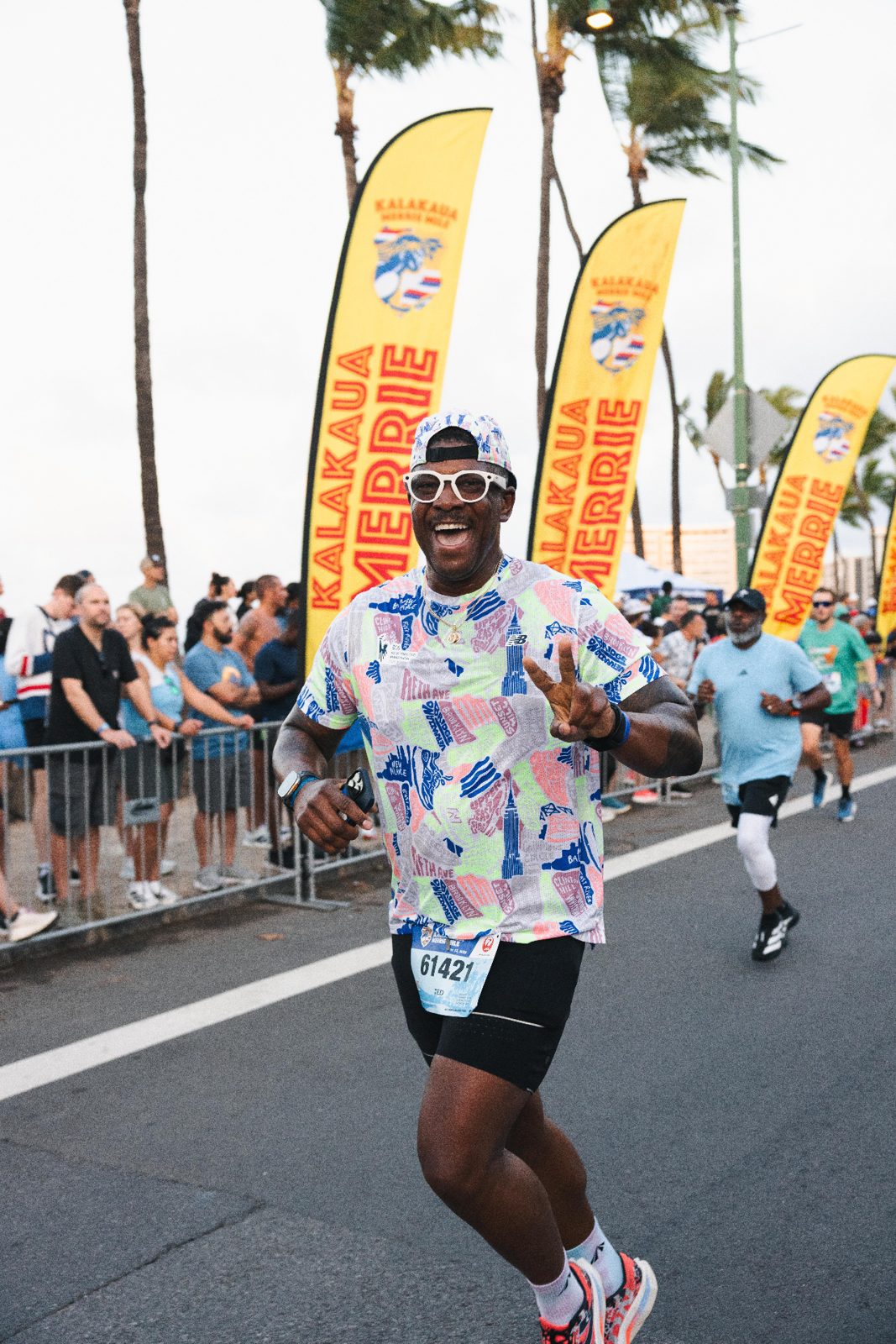 Runner celebrates past Kalakaua Merrie Mile banners on the course