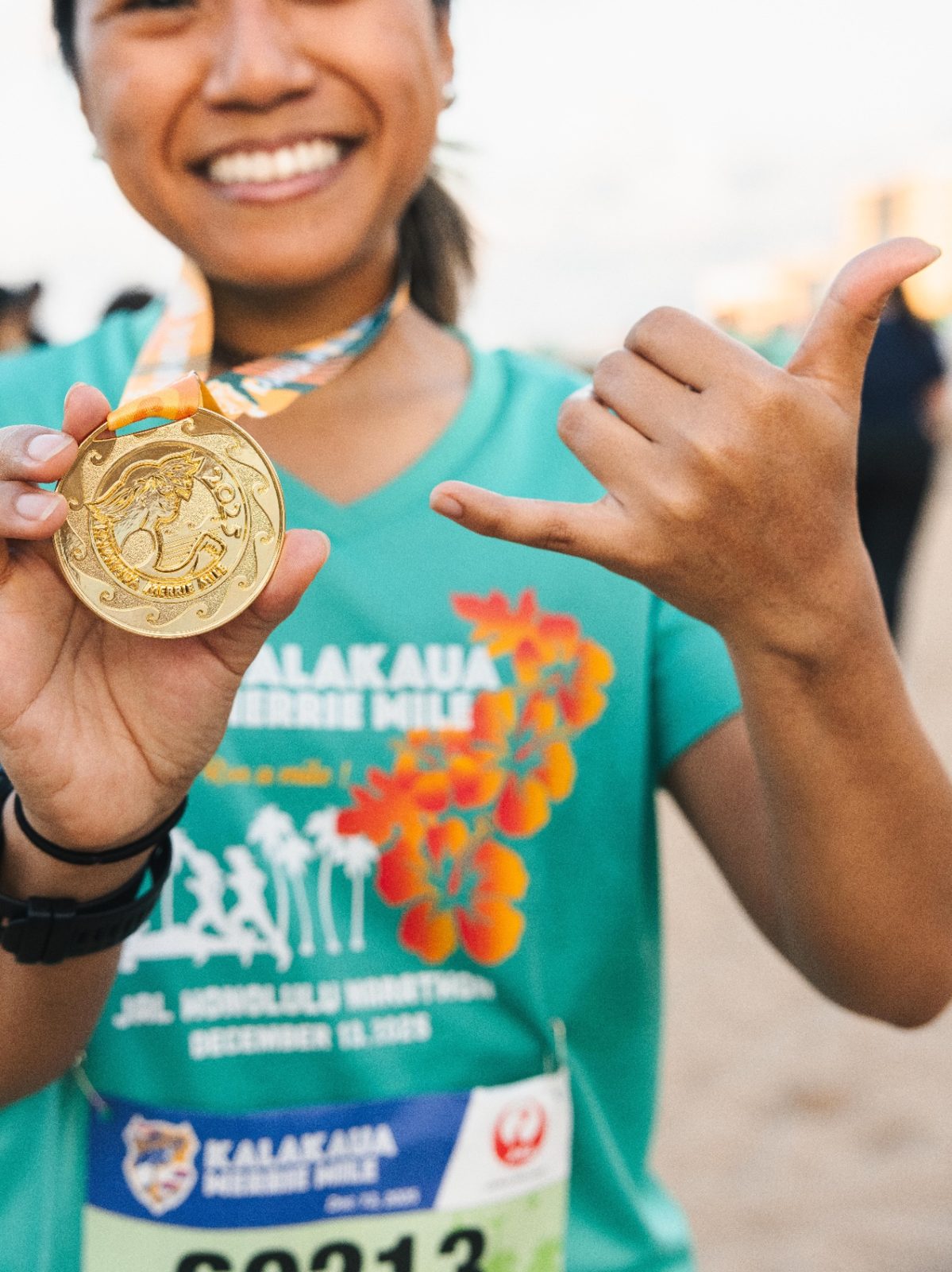 Finisher with shaka and 2025 Kalakaua Merrie Mile medal